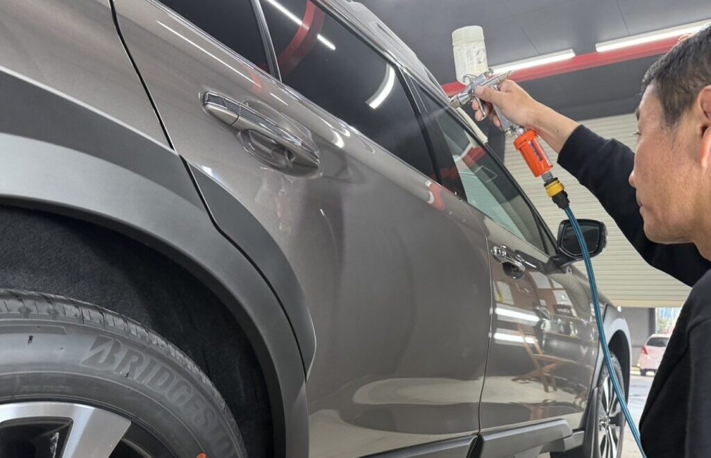 ドア部分にガンスプレーでコーティング剤を吹きかけている様子