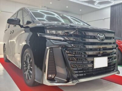 Black Toyota minivan on a showroom floor, polished and on display with a chrome front grille.