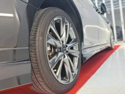 Close-up of a modern car wheel and tire on a red showroom carpet.] ,