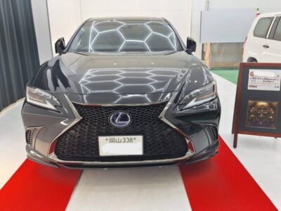 Front view of a black Lexus sedan on a red showroom carpet, facing the camera.