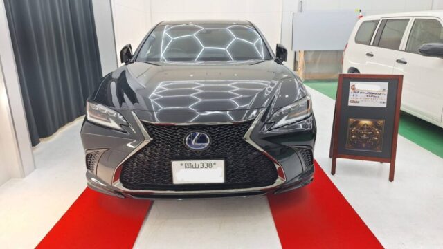 Front view of a black Lexus sedan on a red showroom carpet, facing the camera.