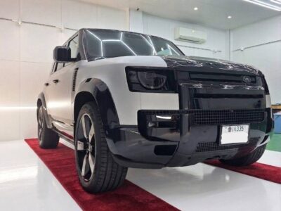 Two-tone white and black Range Rover SUV on a red showroom carpet, photographed from the front corner.