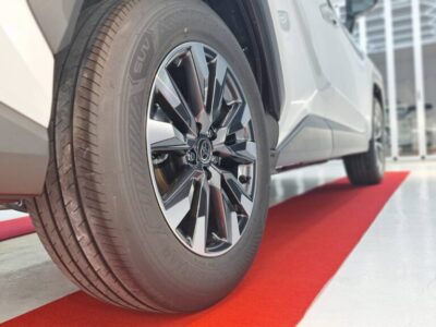 Close-up of a car tire and chrome alloy wheel on a red showroom floor.
