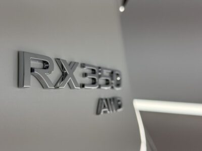 Close-up of a chrome RX350 AWD badge on a light gray car panel.