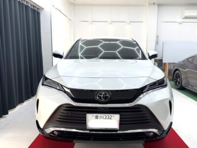 Front view of a white Toyota SUV parked indoors on a red carpet, showroom lighting reflected on the windshield.