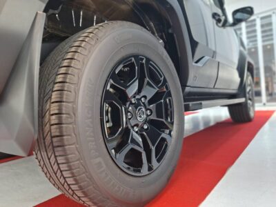 Close-up of a tire and glossy black alloy wheel with a Toyota center cap on a gray truck in a showroom.