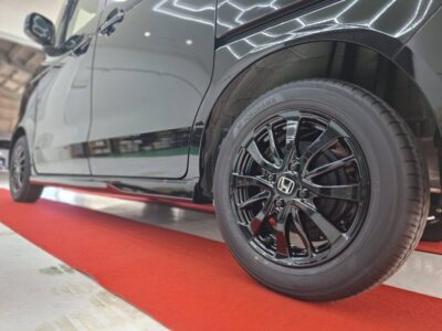 Close-up of a black car wheel with a glossy multi-spoke alloy rim on a red showroom carpet.