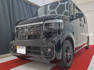 Front three-quarter view of a black Honda minivan on a red showroom carpet, indoors.