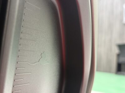 Close-up of a car wheel hub showing a small embossed logo and textured surface.